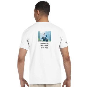 Puede incluir: Camiseta blanca con un gráfico en la espalda que muestra a una persona montada en un oso en un bosque, con el texto "MEMORIES FIRST. PROOF FOR SURE. SAFETY. MAYBE." La camiseta también tiene texto en la manga derecha.