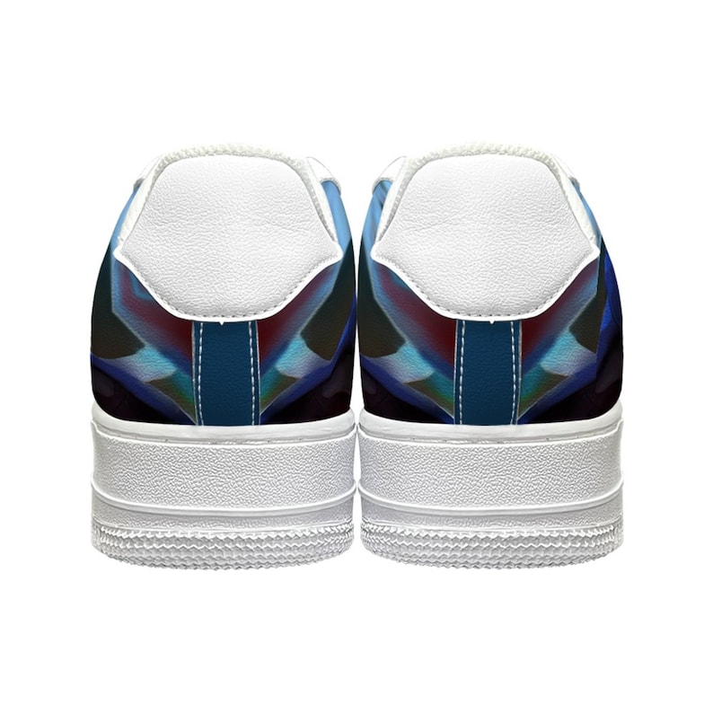 Op de afbeelding: Paar witte sneakers met een kleurrijk geometrisch ontwerp op de hiel. Het ontwerp heeft tinten blauw, rood en zwart. De schoenen hebben witte zolen en witte hielstukken.