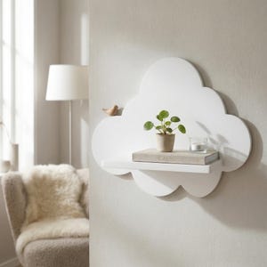 May include: A white cloud-shaped shelf fixed to a wall, displaying a small potted plant, a book with the word "CALM", and a small glass candle holder. A wooden bird is attached to the cloud. The shelf is a decorative item.