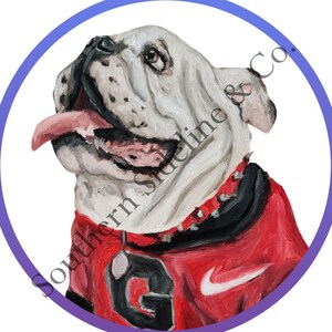 K&ouml;nnte beinhalten: Gemaltes Portr&auml;t einer wei&szlig;en Bulldogge, die ein rot-schwarzes Trikot mit dem Buchstaben "G" und einem Nike-Logo tr&auml;gt. Der Hund hat eine rosa Zunge und befindet sich in einem blau-violetten Kreis. Der Text "Southern Sideline & Co." befindet sich auf dem Bild.