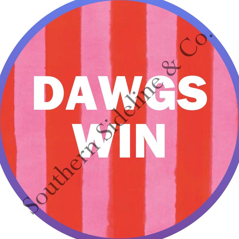 K&ouml;nnte beinhalten: Runder Aufkleber mit einem rot-rosa gestreiften Hintergrund, einem blauen Rand und den wei&szlig;en Worten "DAWGS WIN". Der Text "Southern Sideline & Co." ist am Rand aufgedruckt.