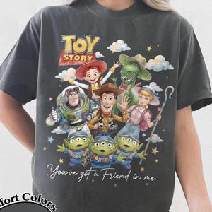 Pu&ograve; includere: T-shirt grigio scuro con una grafica colorata dei personaggi di Toy Story, tra cui Woody, Buzz Lightyear e i piccoli omini verdi. La maglietta presenta la scritta "You've got a Friend in me" e il logo Comfort Colors Pepper.
