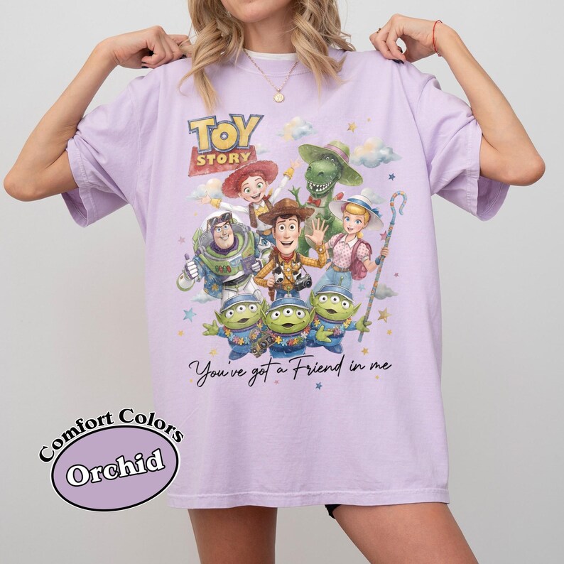 Pu&ograve; includere: T-shirt color orchidea con grafica dei personaggi del film d'animazione "Toy Story". Il design include Woody, Buzz Lightyear e i piccoli omini verdi, con la scritta "You've got a Friend in me".