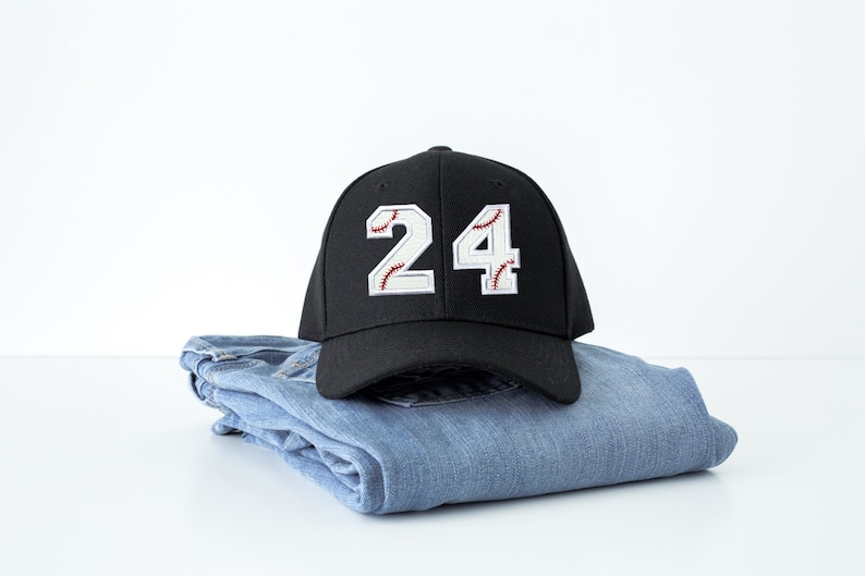 Baseball number patch applied to a black baseball cap showing numbers 2 and 4 with white varsity style jersey numbers and red baseball stitch embroidery. Custom iron on or sew on baseball number patches used for baseball uniforms, team jerseys, little league teams, travel ball players, and personalized sports apparel.