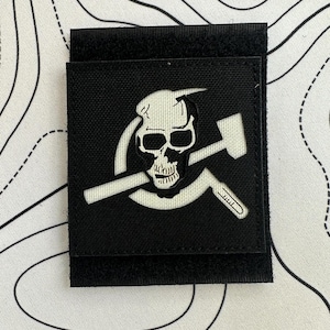 May include: Black patch featuring a white skull with a hammer and a wrench. The skull is centered within a circle, with the tools crossing behind it. The patch has a hook and loop backing for easy attachment.