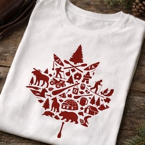 May include: A white short-sleeved t-shirt featuring a large red graphic in the shape of a maple leaf. The leaf is composed of various small silhouettes including a moose, bear, igloo, pine trees, canoe, paddles, and outdoor activity icons.