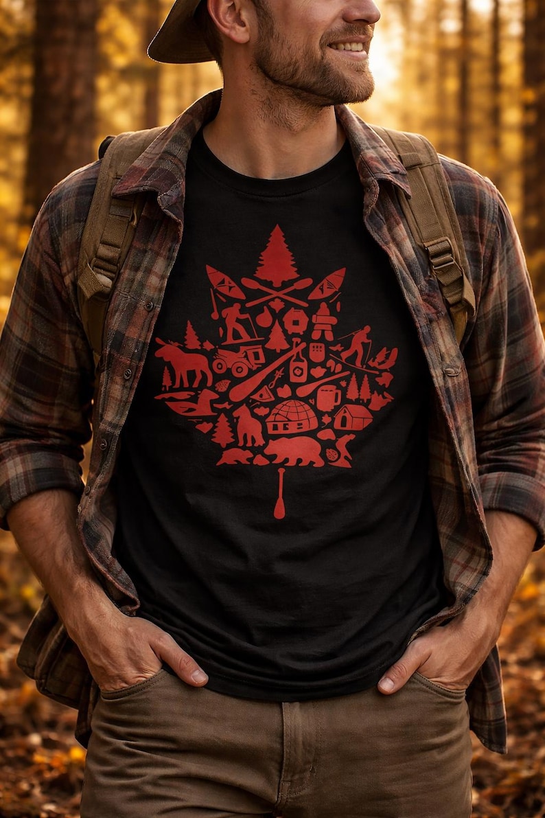 May include: A black short-sleeved t-shirt featuring a large red graphic in the shape of a maple leaf. The graphic is composed of various small icons including a bear, a moose, an igloo, a pine tree, a canoe paddle, and outdoor activity silhouettes.