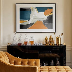 May include: A black bar cabinet with gold bar tools, cocktail shakers, and crystal decanters. An abstract painting hangs above the bar. A tufted, mustard-colored chaise lounge is in the foreground.