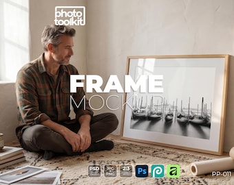 Mockup di cornice PSD / Uomo accanto a una cornice in legno naturale sul pavimento / Studio minimalista / Interni boho / Mockup di stampa artistica