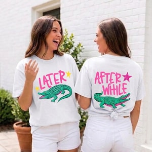 May include: Two white t-shirts with matching designs. The front of one shirt says "LATER" above a green alligator graphic, and the other says "AFTER WHILE". Both shirts have a star graphic. The shirts are paired with white shorts.