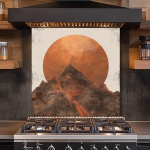 Könnte beinhalten: Eine Küchenrückwand mit einer Bergkette und einer großen orangefarbenen Sonne im Hintergrund. Das Kunstwerk hat einen strukturierten, künstlerischen Stil. Die Rückwand ist über einem schwarzen Gasherd installiert.