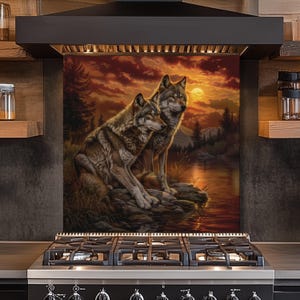 Puede incluir: Un protector contra salpicaduras de cocina decorativo con una pintura de dos lobos. La obra de arte representa a los lobos cerca de un cuerpo de agua, con una puesta de sol en el fondo. La paleta de colores incluye tonos de marrón, naranja y amarillo.