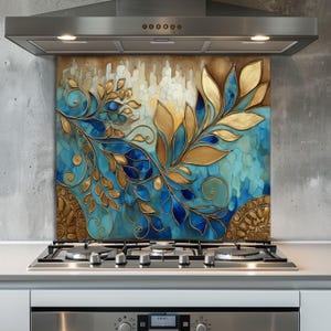May include: A decorative kitchen backsplash featuring a floral design in shades of gold, blue, and turquoise. The artwork has a textured appearance and is installed behind a gas stovetop and beneath a stainless steel range hood.