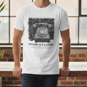 Könnte beinhalten: Weißes T-Shirt mit einer schwarz-weißen Grafik eines alten Wählscheibentelefons. Die Grafik ist vor einem Leiterplattendesign platziert. Der Text "OFFLINE IS A LUXURY" ist darunter gedruckt.