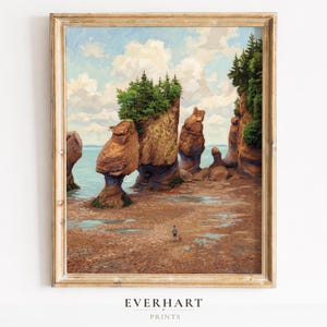 May include: A framed art print depicting a coastal landscape with tall, weathered rock formations topped with green pine trees. A small figure and a dog stand on the sandy beach at low tide. The sky is filled with white clouds above the blue water.