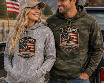 May include: A gray mottled hoodie and a green camouflage hoodie, both featuring a graphic of a cowboy on a horse over an American flag with the text Courtesy of the Red, White and Blue. Each hoodie is paired with a baseball cap with a leather patch.