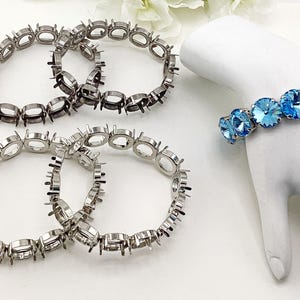 May include: Four silver-toned metal bracelet settings with empty circular prongs for stone mounting, and one finished bracelet featuring bright blue circular faceted stones set in a silver-toned metal chain on a white display form.