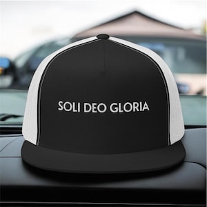 May include: Black and white trucker hat with the embroidered text "SOLI DEO GLORIA" in white. The hat features a black brim and crown, with a white mesh back panel. The hat is a classic style, suitable for casual wear.