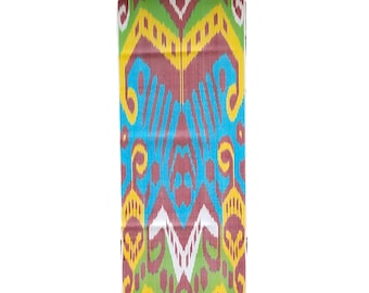 May include: A rectangular textile with a vibrant, symmetrical pattern. The design features repeating motifs in shades of blue, burgundy, yellow, green, and white. The fabric appears to be tightly woven, showcasing a detailed and colorful design.