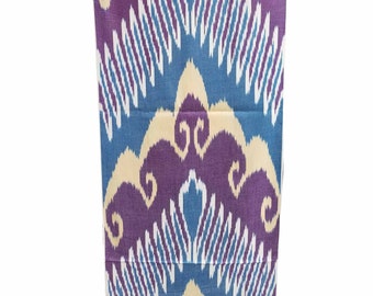 May include: A rectangular textile with a repeating pattern in shades of blue, purple, and cream. The design features stylized floral or geometric shapes, creating a symmetrical and visually appealing composition. The fabric appears to be tightly woven.