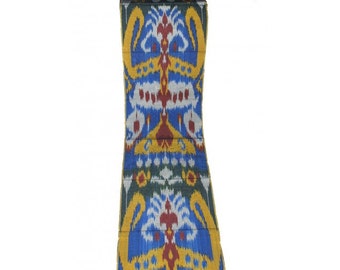 May include: A rectangular textile with a symmetrical pattern. The design features blue, yellow, red, and white shapes on a dark green background. The fabric appears to be woven with a detailed, repeating motif.