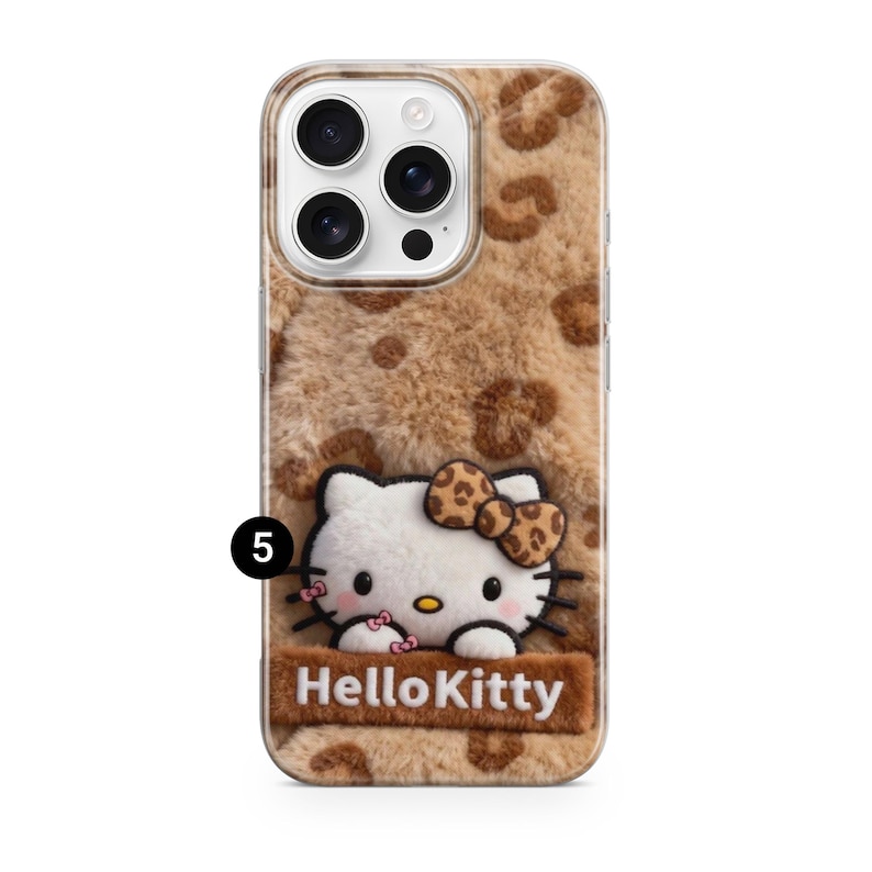 Może przedstawiać: Etui na telefon z brązowym wzorem w cętki. Etui posiada postać Hello Kitty 3D z kokardą i napisem "Hello Kitty". Etui jest przeznaczone do smartfona.