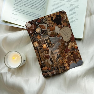 May include: A rectangular tablet case featuring a collage of autumn-themed imagery including a black cat, pumpkins, a ghost, fallen leaves, a coffee cup, a street lamp, Big Ben, and candles, with text reading Autumn kissed the earth.