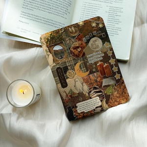 May include: A rectangular e-reader cover featuring an autumn-themed collage with images of a moon, ghosts, a black cat, books, and candles. The cover includes text such as "Autumn," "BOOKS," and "Autumn killed the Summer with the softest kiss."