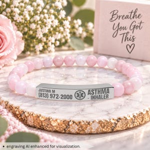Puede incluir: Una pulsera elástica con cuentas esféricas de color rosa claro y blanco y una placa de identificación médica de metal plateado. La placa está grabada con el texto JUSTINA M, (813) 972-2000, un símbolo médico y ASTHMA - INHALER.
