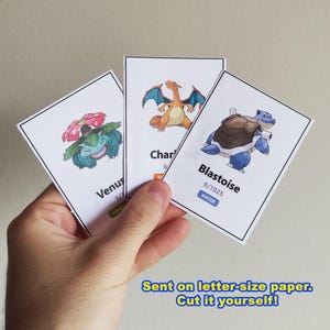 Pu&ograve; includere: Tre carte collezionabili di Pok&eacute;mon con Venusaur, Charizard e Blastoise. La carta Venusaur ha un design verde e rosa, la carta Charizard ha un design arancione e blu e la carta Blastoise ha un design blu e marrone. Il testo sulle carte include i nomi e i numeri.