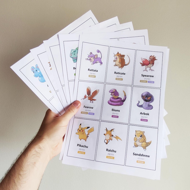 Pu&ograve; includere: Un ventaglio di carte stampate con illustrazioni di personaggi di cartoni animati colorati. Ogni carta mostra un nome e un numero. Le carte presentano personaggi come Pikachu, Raichu e Sandshrew, su uno sfondo neutro.