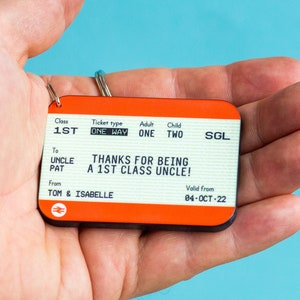 May include: A red and white train ticket keychain with the text "Thanks for being a 1st class uncle!" and "Valid from 04-OCT-22".