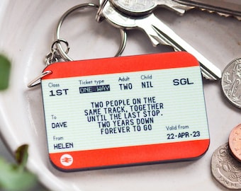 May include: A red and white train ticket keychain with the text "Two people on the same track, together until the last stop. Two years down forever to go." The ticket is labelled "1st Class" and "One Way" and has the names "Dave" and "Helen" printed on it.