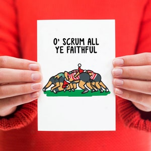 May include: A white card with the text "O' SCRUM ALL YE FAITHFUL" in black lettering. A cartoon image of a rugby scrum with players wearing red and green jerseys and Santa hats.