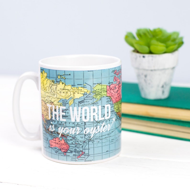 May include: White ceramic mug with a world map design and the text "THE WORLD is your oyster" in white. The map is in shades of blue, green, yellow, and red.