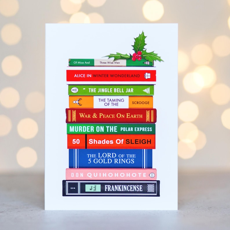 Christmas cards book puns made by oflifeandlemons. 10 books are stacked with the spine facing forward with a mistletoe on top of the stack