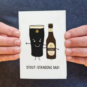 May include: A white card with a cartoon illustration of a pint of stout and a bottle of stout. The pint of stout is holding a bottle of stout with both arms. The text on the card reads "Stout-standing Dad!"