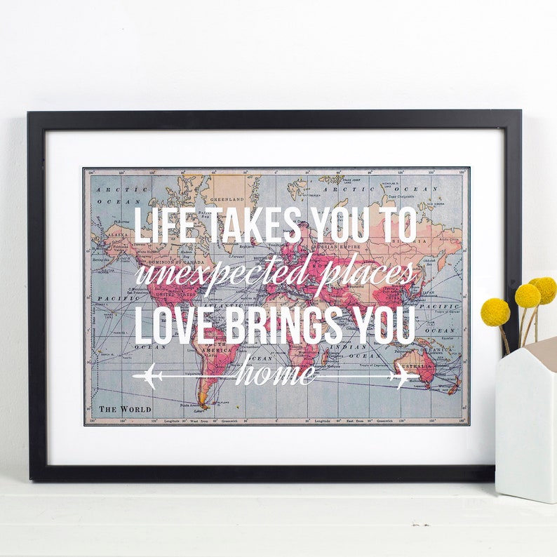 Op de afbeelding: Een ingelijst afdruk met een vintage wereldkaart en de tekst "LIFE TAKES YOU TO unexpected places LOVE BRINGS YOU home".