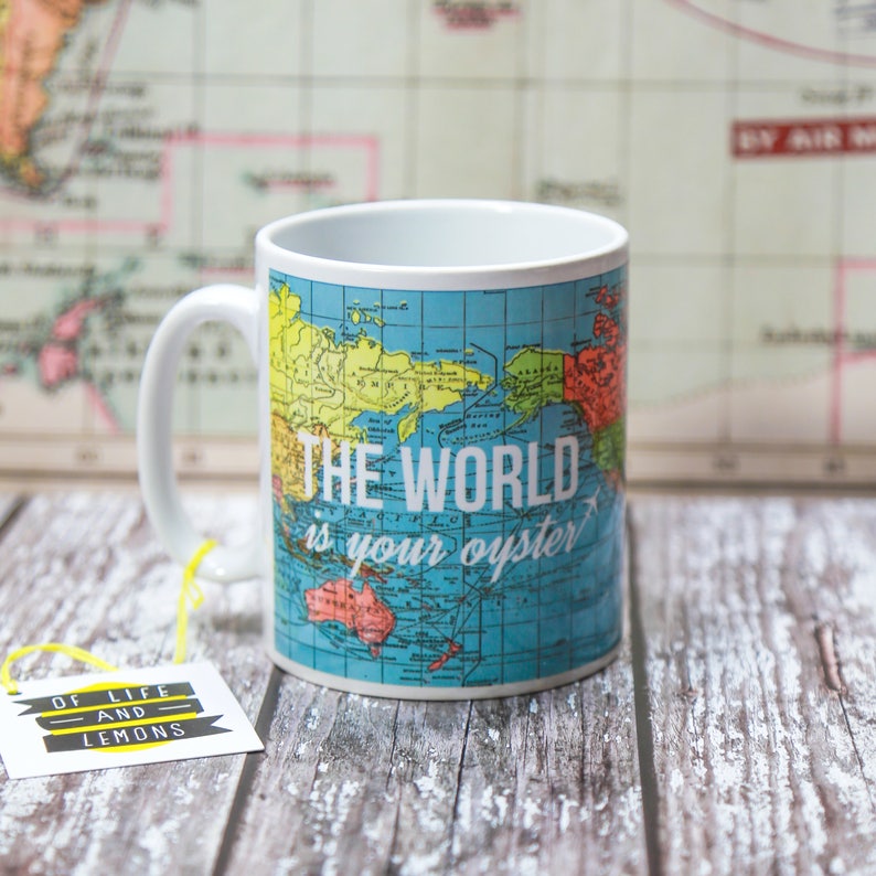 May include: A white ceramic mug with a blue and yellow world map design. The mug has a handle and the text "THE WORLD is your oyster" printed on the front.