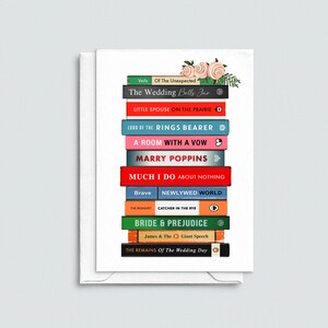 Pode incluir: Um cart&atilde;o com uma pilha de lombadas de livros coloridos com t&iacute;tulos como "Bride & Prejudice" e "Marry Poppins". O cart&atilde;o &eacute; adornado com um arranjo floral de rosas cor-de-rosa e folhas verdes. Fundo branco.