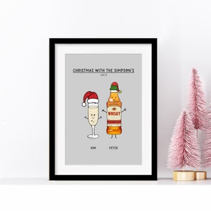 May include: A framed print with a grey background featuring a cartoon illustration of a champagne glass and a bottle of whisky wearing Santa hats. The text "Christmas with the Simpson's 2023" is at the top of the print. The names "Kim" and "Peter" are below the cartoon characters.