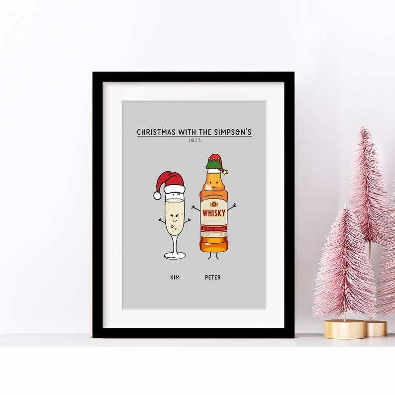 May include: A framed print with a grey background featuring a cartoon illustration of a champagne glass and a bottle of whisky wearing Santa hats. The text "Christmas with the Simpson's 2023" is at the top of the print. The names "Kim" and "Peter" are below the cartoon characters.