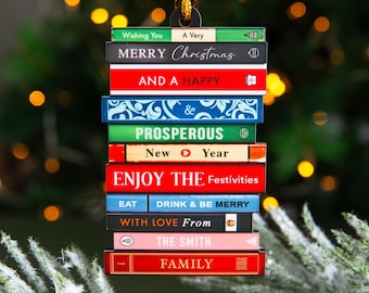 May include: A flat, rectangular hanging ornament shaped like a stack of books with a gold cord. The spines feature text including "Wishing You A Very MERRY Christmas AND A HAPPY PROSPEROUS New Year ENJOY THE Festivities EAT DRINK & BE MERRY WITH LOVE From THE SMITH FAMILY."