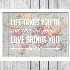 Op de afbeelding: Een vintage wereldkaart met de tekst "Life takes you to unexpected places, love brings you home" eroverheen gelegd. De kaart bevindt zich in een wit kader.