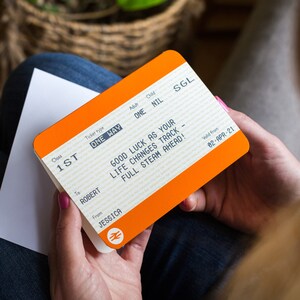 Peut inclure: Un billet de train orange vif avec les mots "1ST", "ONE WAY", "SGL", "GOOD LUCK AS YOUR LIFE CHANGES TRACK - FULL STEAM AHEAD!" et "Valid from 02-APR-21".
