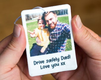May include: White car air freshener with a photo of a father and son. The text reads "Drive safely Dad! Love you xx".