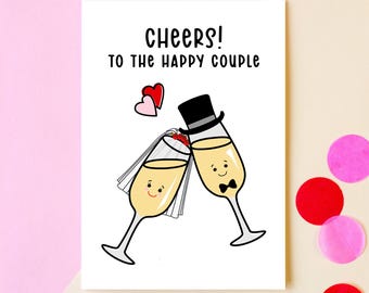 Pode incluir: Um cartão branco com o texto "Cheers! To the happy couple" e uma ilustração de desenho animado de duas taças de champanhe com rostos. As taças brindam, e uma tem um véu e a outra um chapéu-coco. Há dois corações vermelhos no canto superior esquerdo.