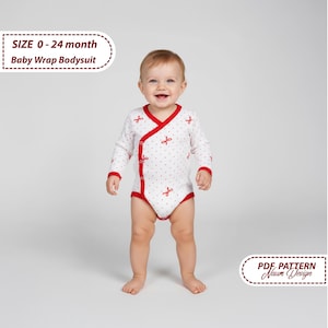 Könnte beinhalten: Weißer Baby-Wickelbody mit roten Verzierungen und Schleifenmotiven. Der langärmlige Body hat ein Wickeldesign und ist für Babys von 0-24 Monaten geeignet. Der Text "SIZE 0-24 month Baby Wrap Bodysuit" ist sichtbar.