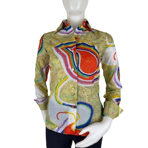 May include: A long-sleeved button-down shirt featuring a vibrant, multi-colored abstract marble pattern. The design includes swirling shapes in red, blue, yellow, and green against a textured, light-colored background. It has a classic collar.