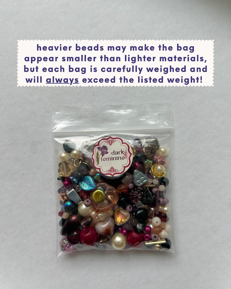 May include: A clear plastic bag filled with an assortment of multi-colored beads in various shapes and sizes. A circular white label with a purple flower graphic and the text "dark feminine" is attached. Text above reads: heavier beads may make the bag appear smaller than lighter materials, but each bag is carefully weighed and will always exceed the listed weight!